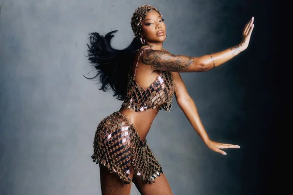 A imagem mostra a cantora Ludmilla fotografada em um fundo cinza vestida em paetê