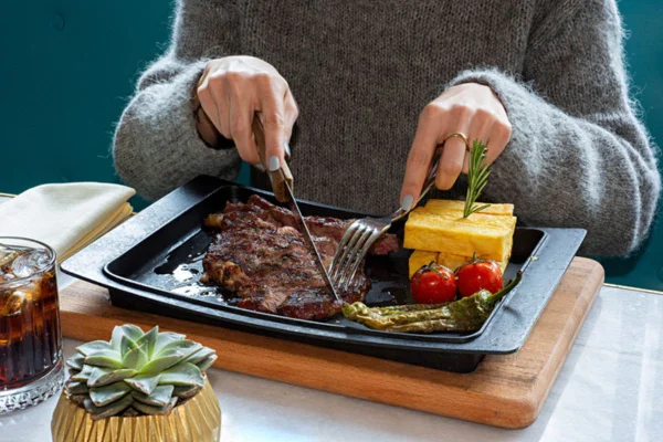 Imagem colorida de mulher comendo carne