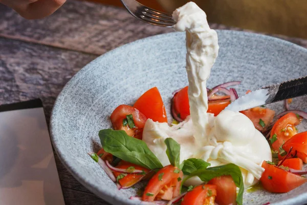 prato com burrata partida, tomates e manjericão