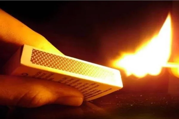 Imagem mostra homem acendendo palito de fósforo, que mostra uma chama - Metrópoles