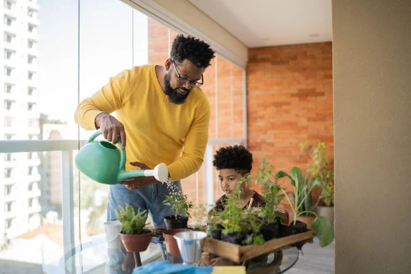 pai e filho cultivando planta em casa