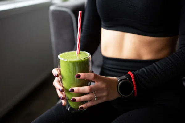 Imagem colorida de mulher bebendo suco verde
