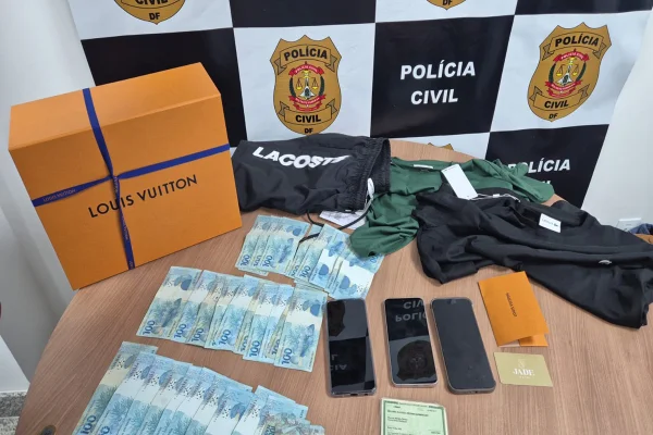Foto colorida com dinheiro, celulares e roupas de luxo apreendidas