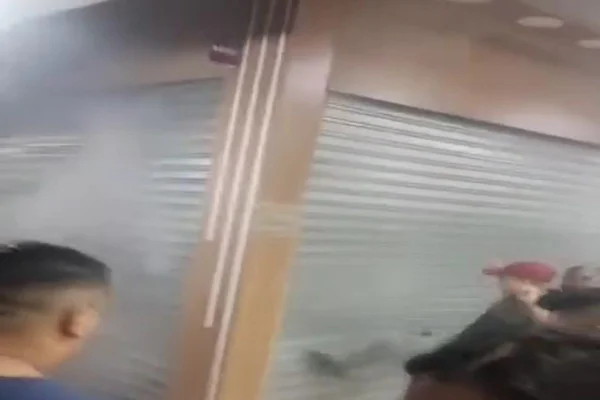 Imagem colorida mostra reprodução de vídeo com comerciantes tentando entrar em box que estava com fumaça saindo da porta - Metrópoles