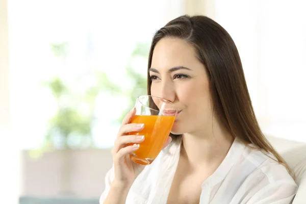 mulher de cabelo escuro bebendo um suco