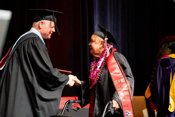 Imagem colorida de idosa recebendo diploma