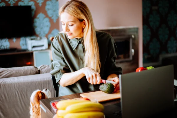 Foto colorida de cão observando tutora cortar abacate, alimento tóxico para pets