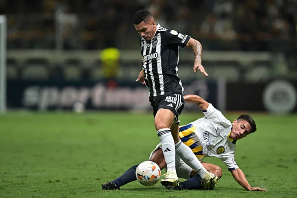 Imagem colorida de Paulinho do Atlético Mineiro driblando jogador do Rosario Central