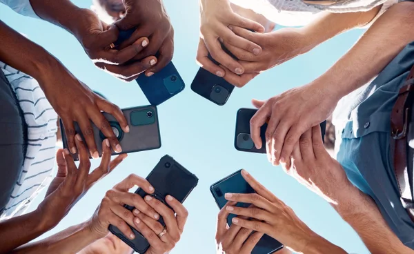 Foto colorida de grupo de pessoas mexendo em celular - Metrópoles