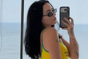 Demi Lovato faz selfie no espelho de óculos escuros e blusa com as cores do Brasil Demi Lovato faz selfie no espelho de óculos escuros e blusa com as cores do Brasil