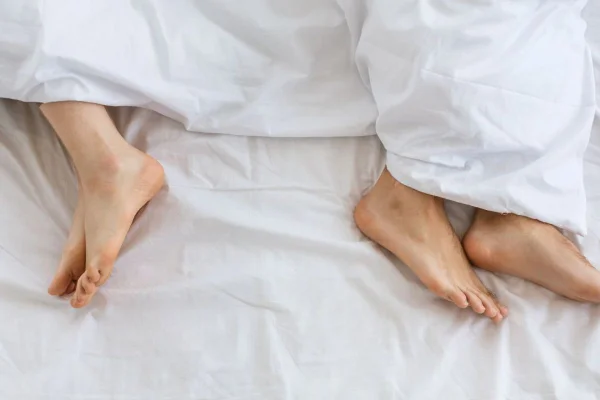 Pessoas deitadas na cama foto aparecendo somente o pé
