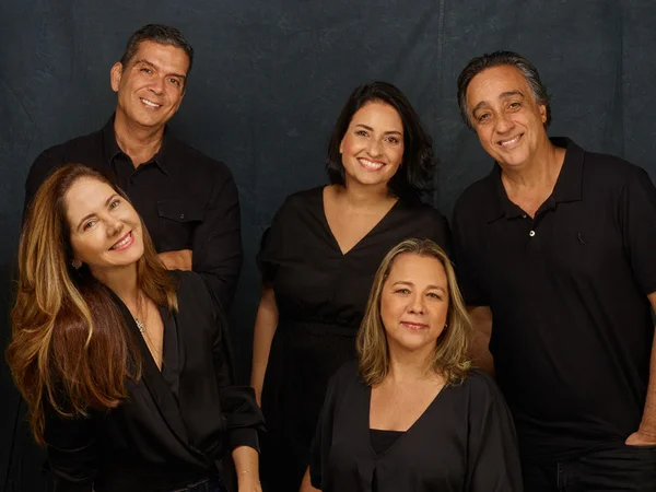 Equipe da empresa Approach Comunicação, todos usando preto sob fundo da mesma cor - Metrópoles