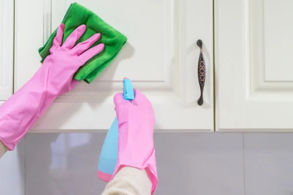foto colorida de pessoa limpando armário de cozinha