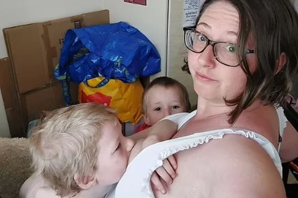 foto colorida de mulher amamentado uma criança e outra olhando