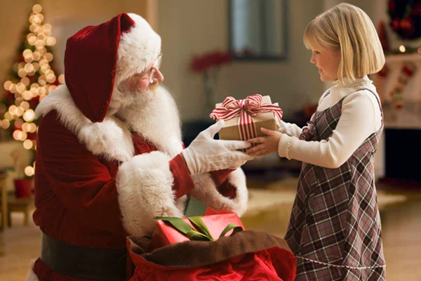 Imagem colorida de papai noel entregando presente para criança - Metrópoles