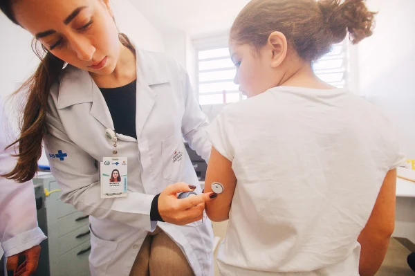 Fotografia colorida mostrando médica colocando sensor de glicose em criança-Metrópoles