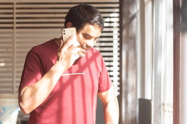 Homem com camisa vinho falando ao celular
