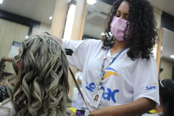 Mulher de mascara corta o cabelo de outra