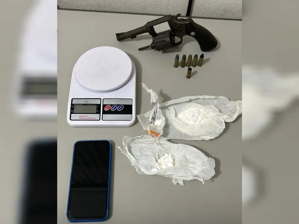 Imagem de balança de precisão, revólver, embalagem com cocaína e celular sobre um mesa - Metrópoles