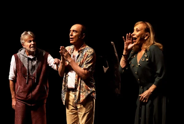 Foto colorida de Arlete Salles. A atriz está no palco do teatro, de roupa preta, e ao lado de dois homens- Metrópoles