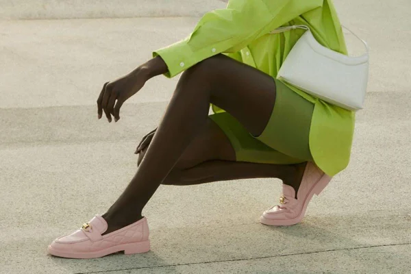 Mulher negra agachada na rua com roupas em cores vibrantes