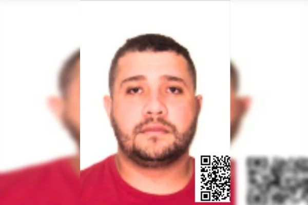 Foto colorida, em estilo 3x4, de homem branco, de barba curta e camiseta vermelha