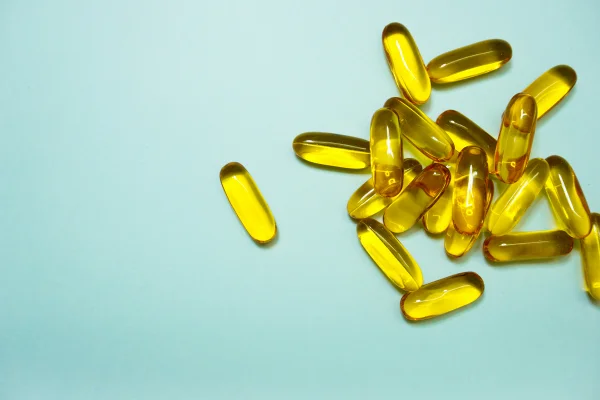Comprimidos de vitamina D em fundo verde claro. Metrópoles
