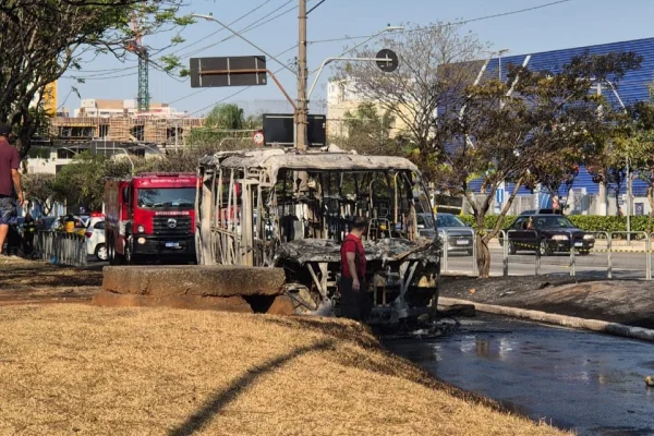 Imagem colorida de carçaça carbonizada de ônibus incendiado. Metrópoles
