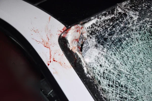 Imagem de para-brisa de carro branco estilhaçado, com manchas de sangue - Metrópoles