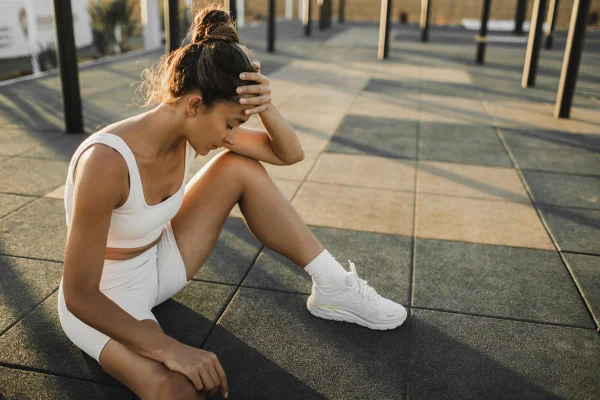 Foto colorida de mulher sentada em tatame de academia - Metrópoles