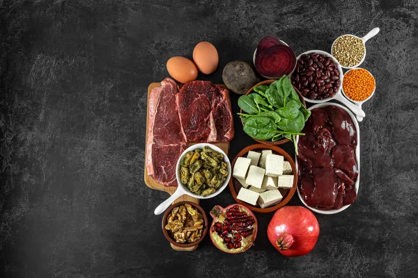 Imagem mostra mesa preta com vários alimentos ricos em ferro, como carnes, frutas e vegetais - Metrópoles