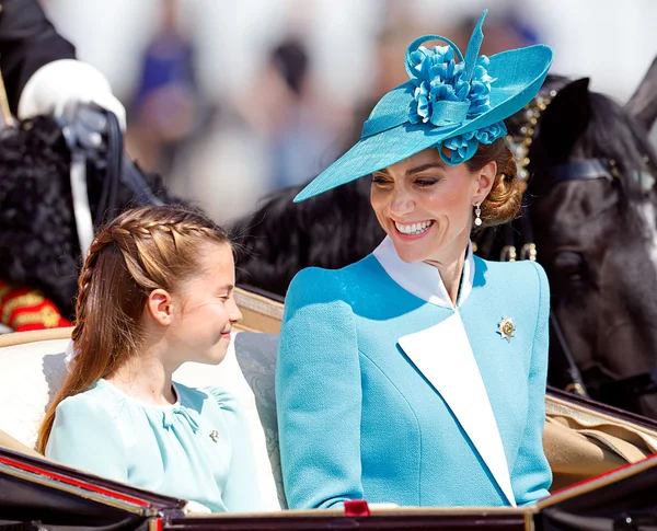 Na foto a princesa Charlotte sorri para a mãe, Kate Middleton. As duas estão em um carruagem