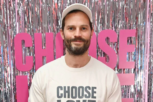foto colorida do ator Jamie Dornan de barba e bone - metrópoles