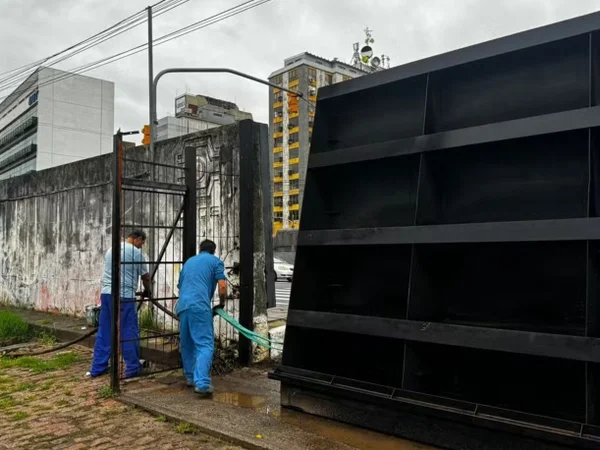 Foto colorida de trabalhadores da prefeitura fecham comportas de sistema de segurança para evitar inundação pelo Guaíba em Porto Alegre - Metrópoles