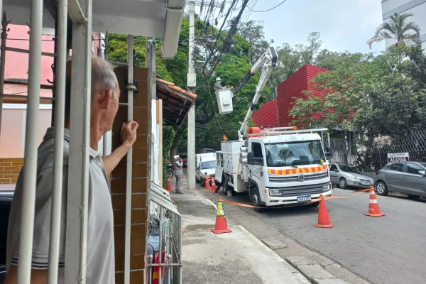 Morador observa caminhão da Enel trabalhando na região do Guarapiranga, zona sul de São Paulo