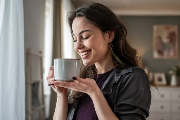 Foto colorida de mulher sorridente segurando xícara de chá - Metrópoles