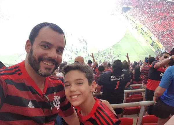 Fotografia colorida mostrando pai e filho em estádio durante jogo do Flamengo-Metrópoles