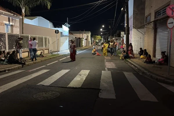 Foto colorida de comunidade cigana em frente a hospital onde vítima baleada durante festa de casamento foi levada e morreu.