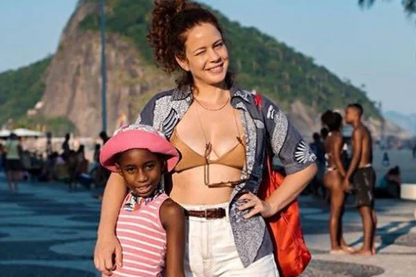 foto colorida de Leandra Leal e a filha Julia, uma menina negra que veste uma roupa rosa - metrópoles
