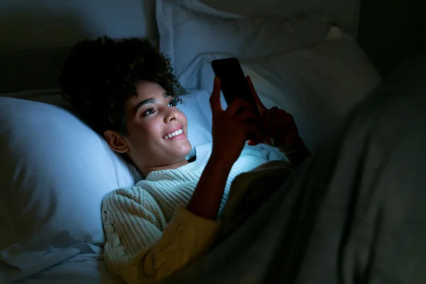 mulher mexendo no celular de noite na cama