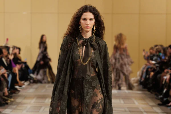 Imagem colorida de mulher desfilando em vestido preto
