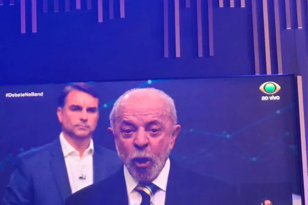 Imagens coloridas mostram Lula e Flávio Bolsonaro sob ótica de lentes da TV Bandeirantes durante debate na emissora