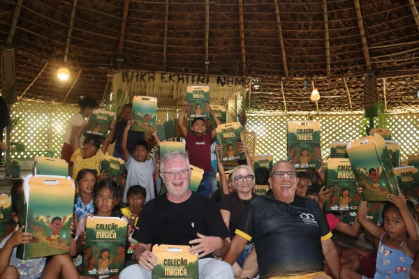 Grupo reunido em ambiente interno, com mesas, caixas e crianças