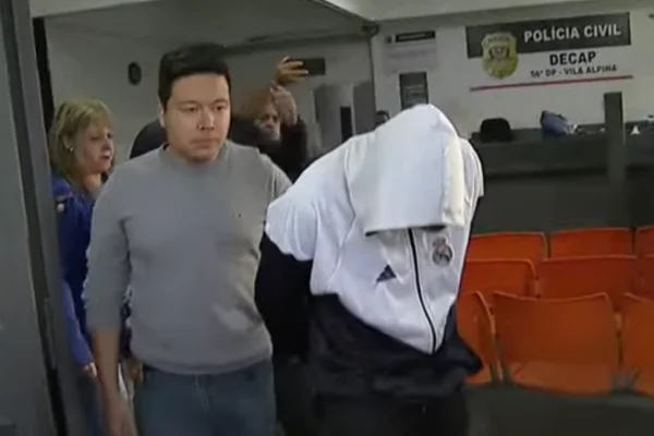 Imagem colorida de homem encapuzado preso na delegacia da Vila Alpina, zona leste de São Paulo. Metrópoles