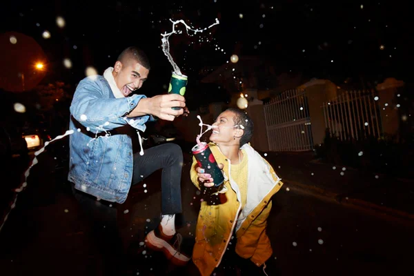 Dois amigos tomando energético muito felizes pulando e sorrindo