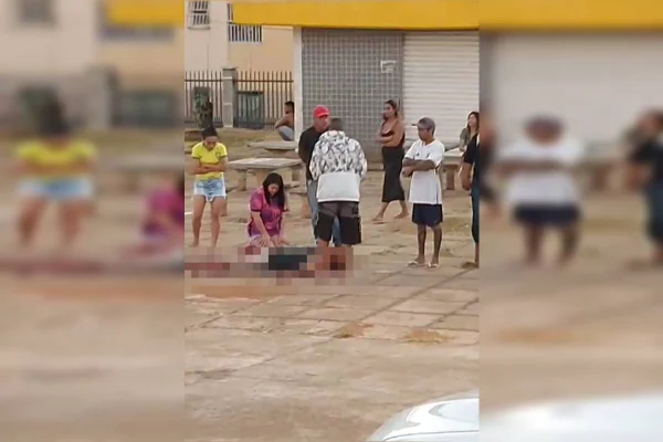 Foto colorida de homem deitado no chao em meio a poça de sangue e pessoas em volta - Metrópoles