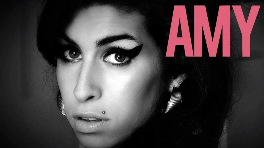 <strong>“Amy” (2015)</strong>: A produção registra o trajeto do promissor início na carreira como cantora de jazz ao estrelato pop. Amy foi também ícone fashion e um dos nomes do British Invasion do começo dos anos 2000. A cantora enfrentou problemas com álcool e drogas (era viciada em crack e heroína). Vários homens do círculo de Winehouse a fizeram definhar: o pai da cantora, Mitch Winehouse, o namorado Blake Fielder-Civil e seu último empresário. A agressividade da mídia sensacionalista que se comprazia a cada recaída da estrela é parte importante do documentário. <a href="https://www.youtube.com/watch?v=Za3lZcrzzcM&feature=youtu.be" target="_blank">Veja trailer</a> <strong>“Amy” (2015)</strong>: A produção registra o trajeto do promissor início na carreira como cantora de jazz ao estrelato pop. Amy foi também ícone fashion e um dos nomes do British Invasion do começo dos anos 2000. A cantora enfrentou problemas com álcool e drogas (era viciada em crack e heroína). Vários homens do círculo de Winehouse a fizeram definhar: o pai da cantora, Mitch Winehouse, o namorado Blake Fielder-Civil e seu último empresário. A agressividade da mídia sensacionalista que se comprazia a cada recaída da estrela é parte importante do documentário. <a href="https://www.youtube.com/watch?v=Za3lZcrzzcM&feature=youtu.be" target="_blank">Veja trailer</a>
