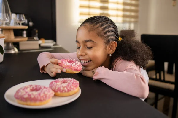 Menina doce apreciando donuts. Conceito de obesidade/diabetes infantil