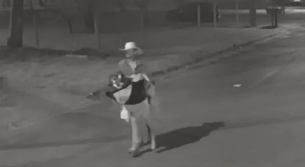 Frame preto e branco de um homem andando no meio da rua com chapéu e roupas no braço - Metrópoles