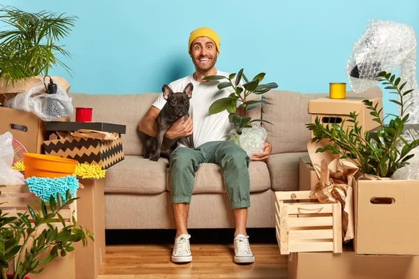 cachorro e homem num sofá rodeados de plantas